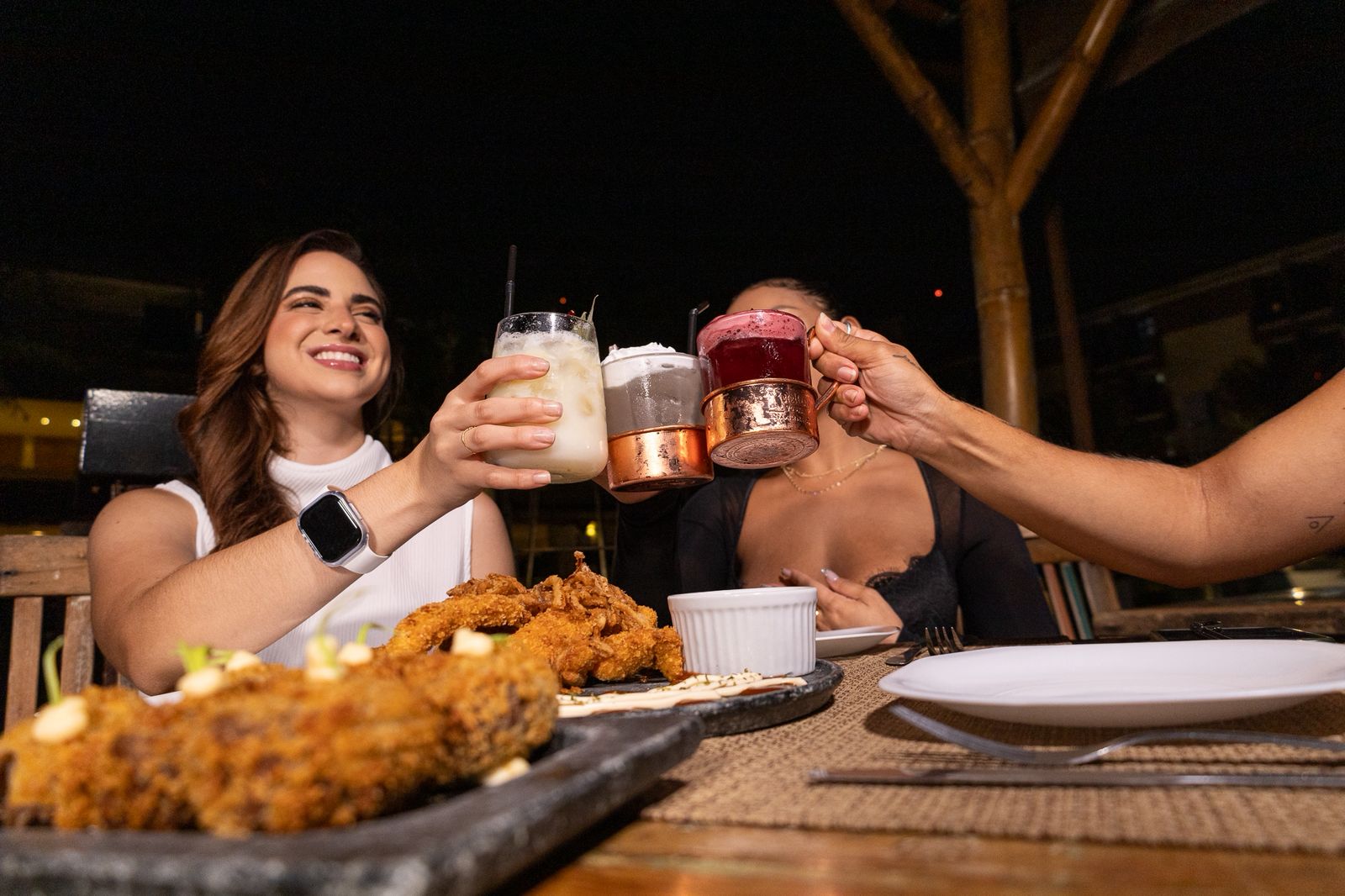 Amigos brindando com drinks variados à noite